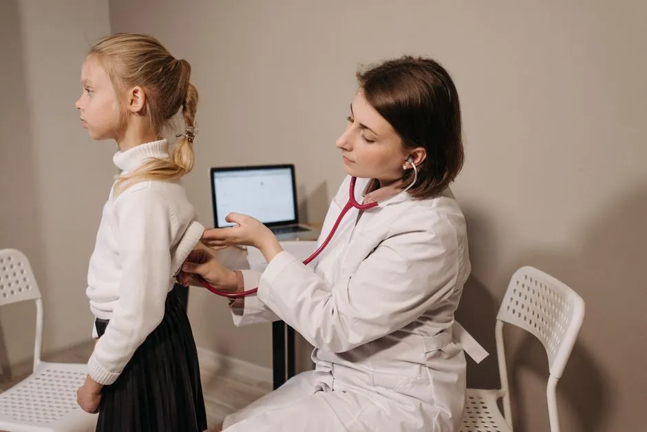 A pediatrician listening to a child's back with a stethoscope during a routine exam