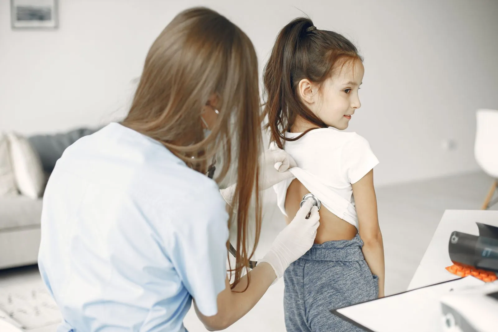A pediatrician using a stethoscope to examine a young child during a checkup